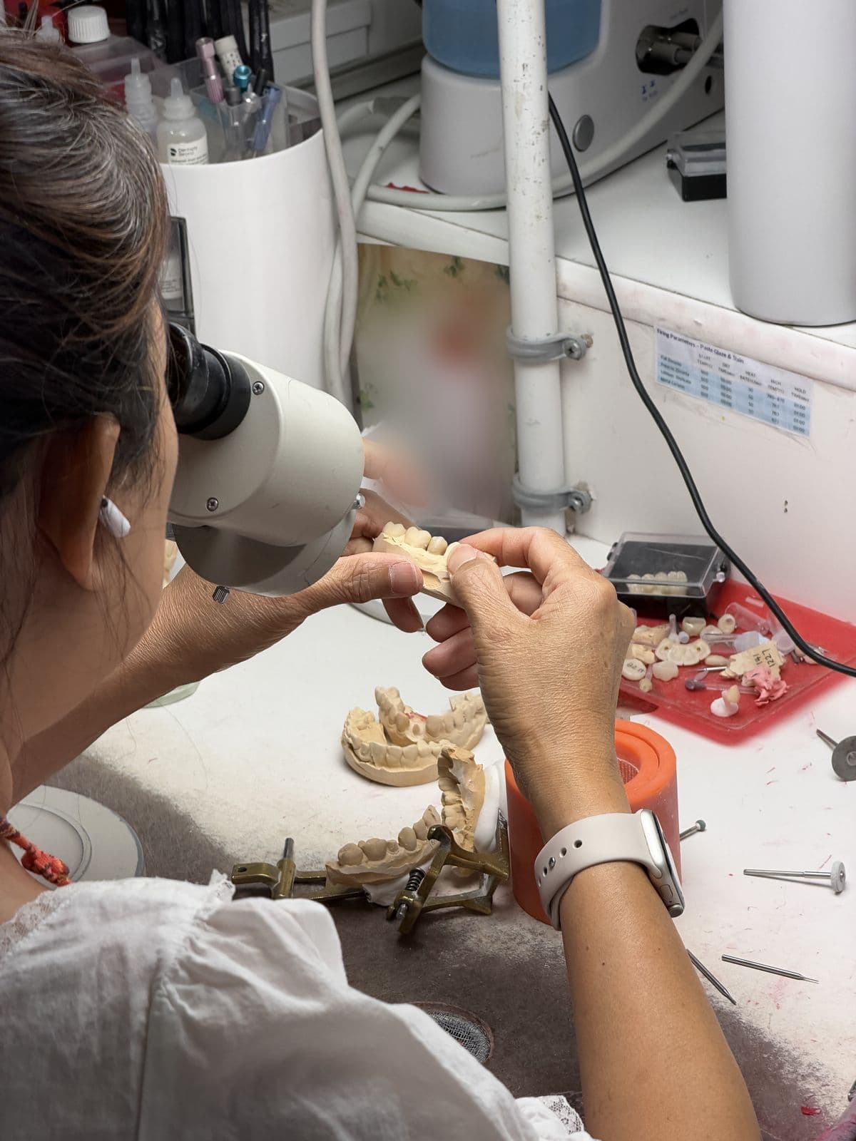 Technician finishing a restoration under a microscope